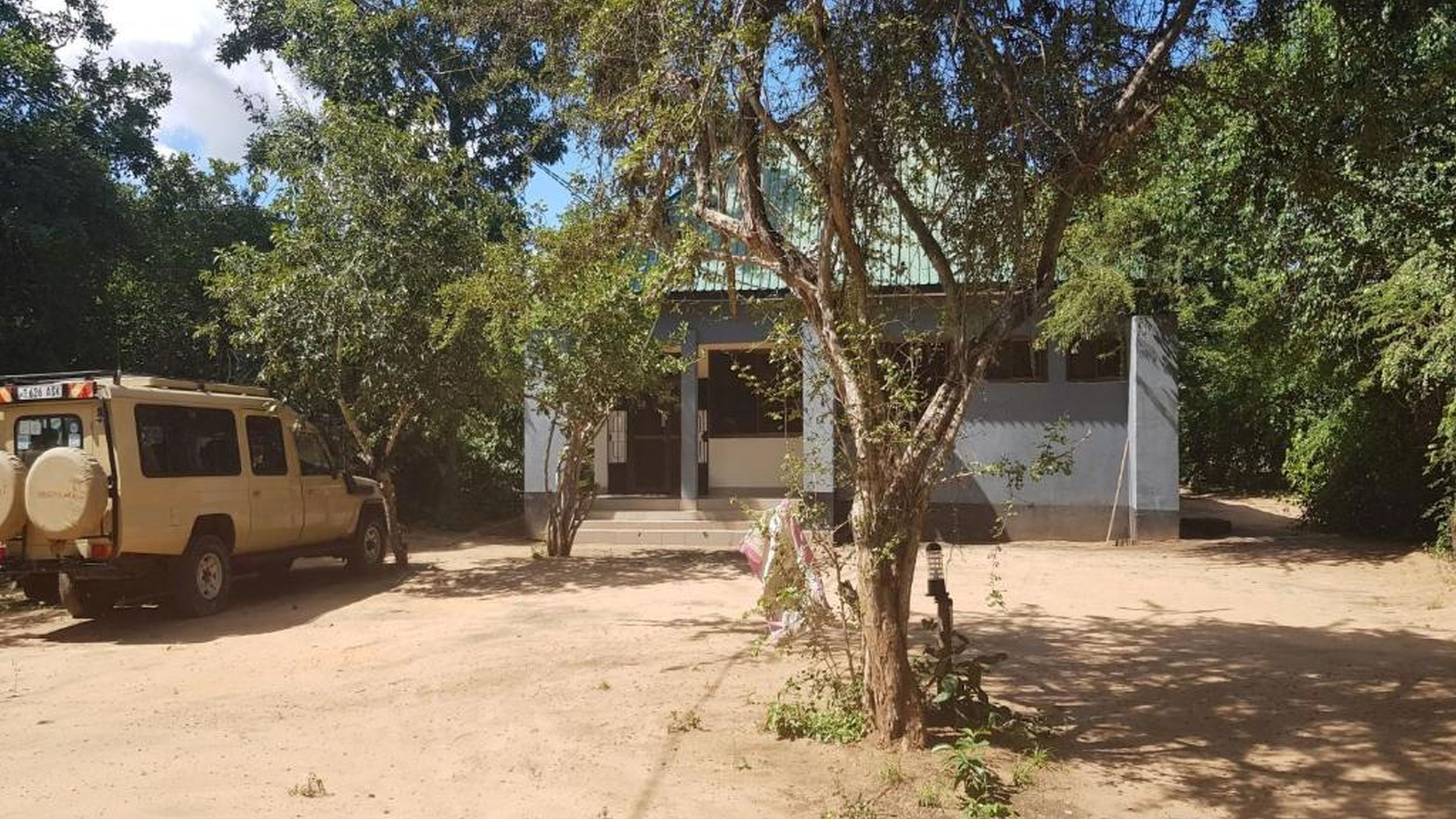 Light-coloured camp building partly screened by trees