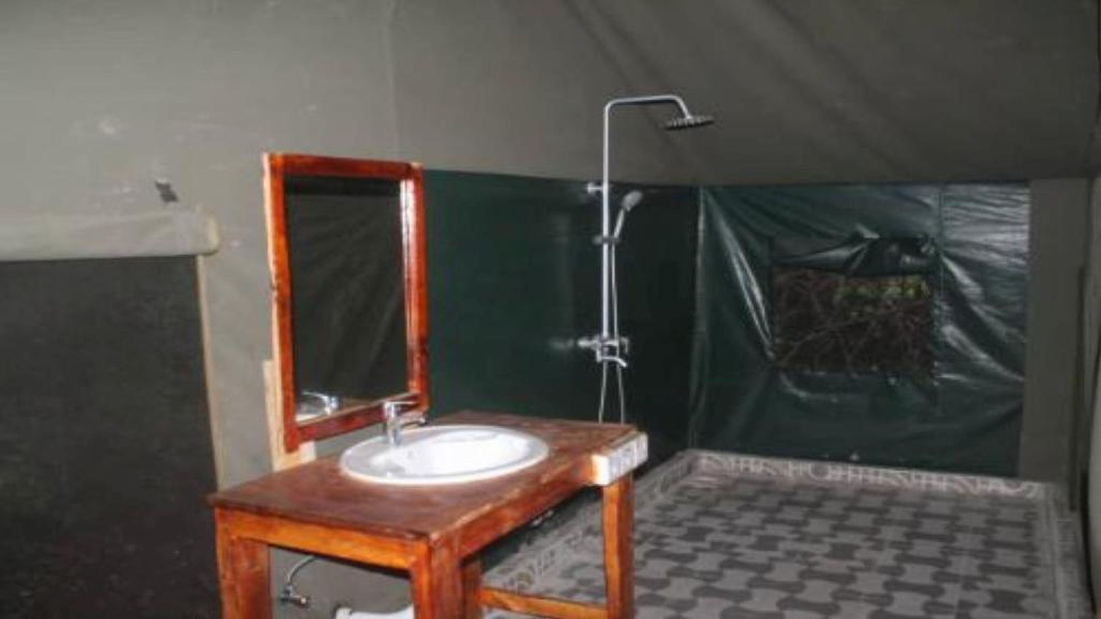 Canvas-walled bathroom with a basin, mirror and shower