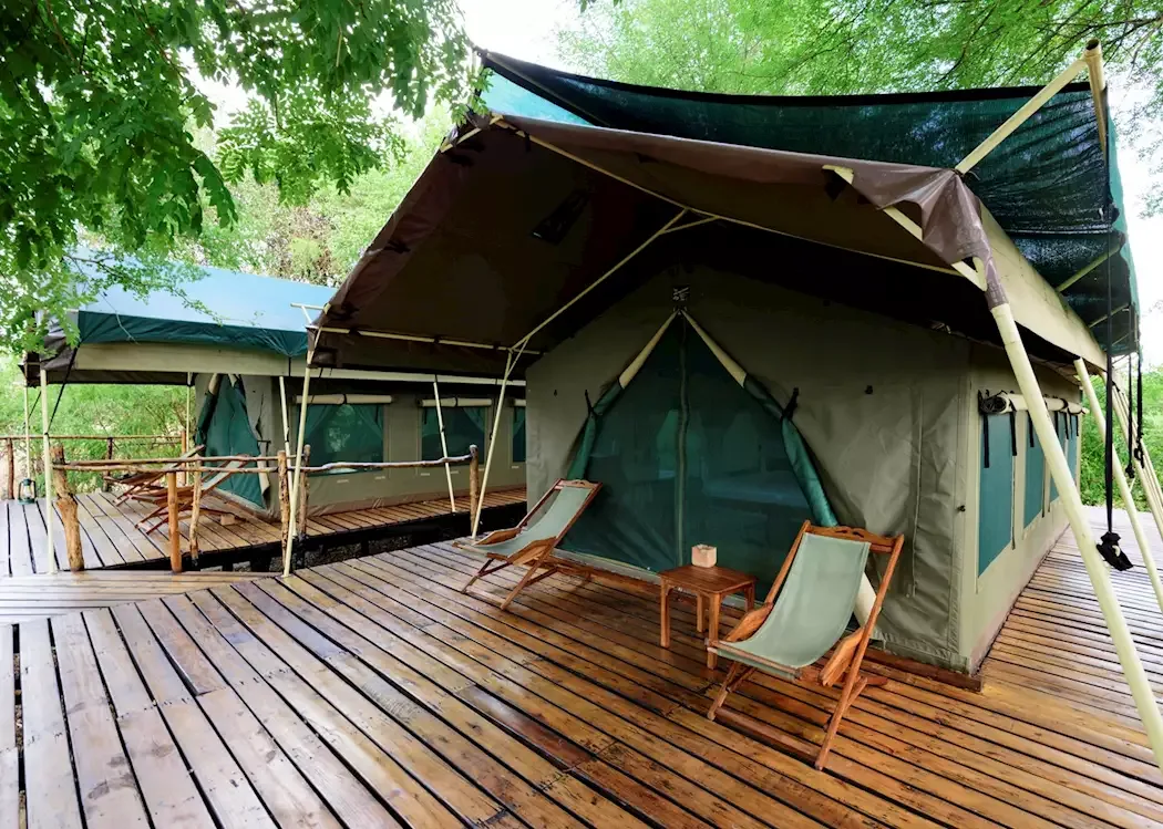 Light-coloured camp building partly screened by trees
