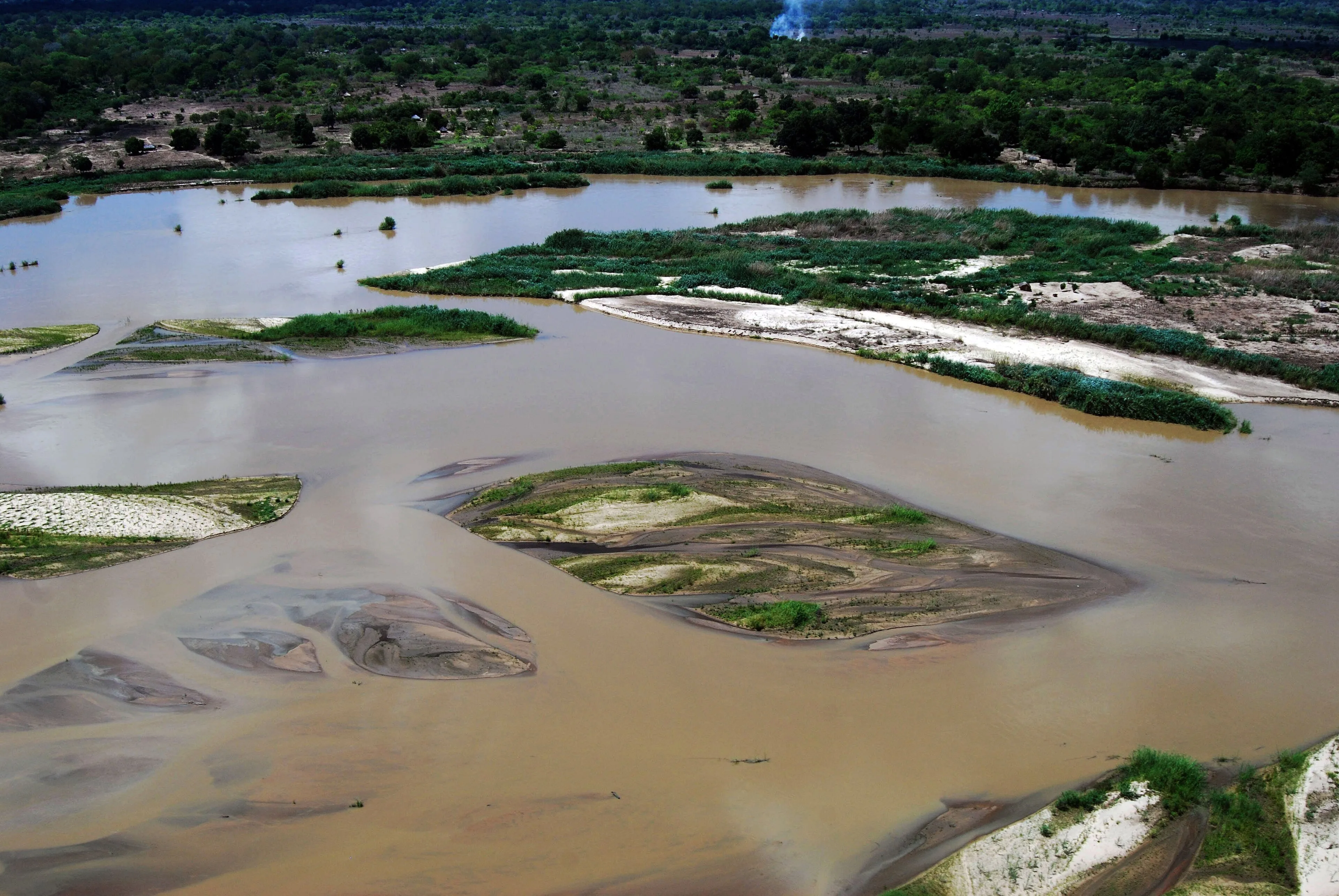 Broad Rufiji River bordered by green vegetation beneath a blue sky